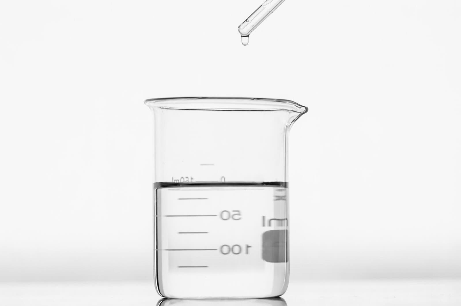 A pipette inside a beaker on top of a table