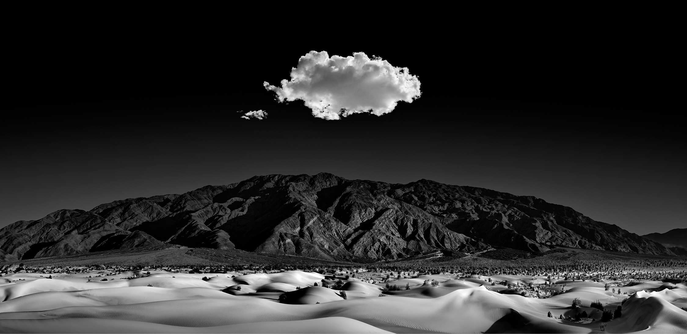 Mesquite dunes of death valley with the Amargosa Mountains in the distance. Curves, patterns, and shadows captured and contrasted in the moonlight. A single cloud hangs above, serenading the evening landscape.