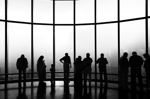 Group of people look out a high rise window 