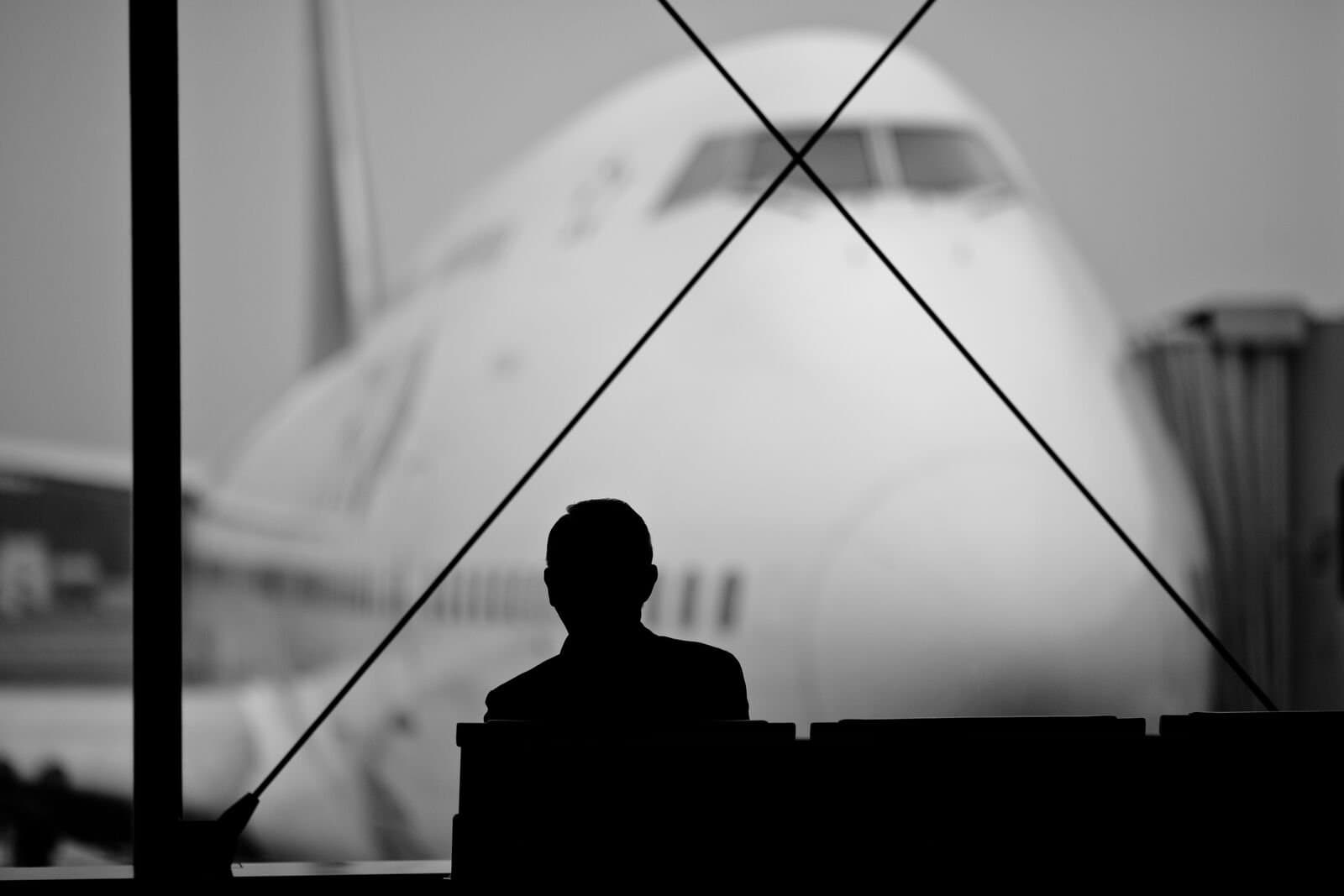 A person sitting at a airport departure gate in front of a plane 