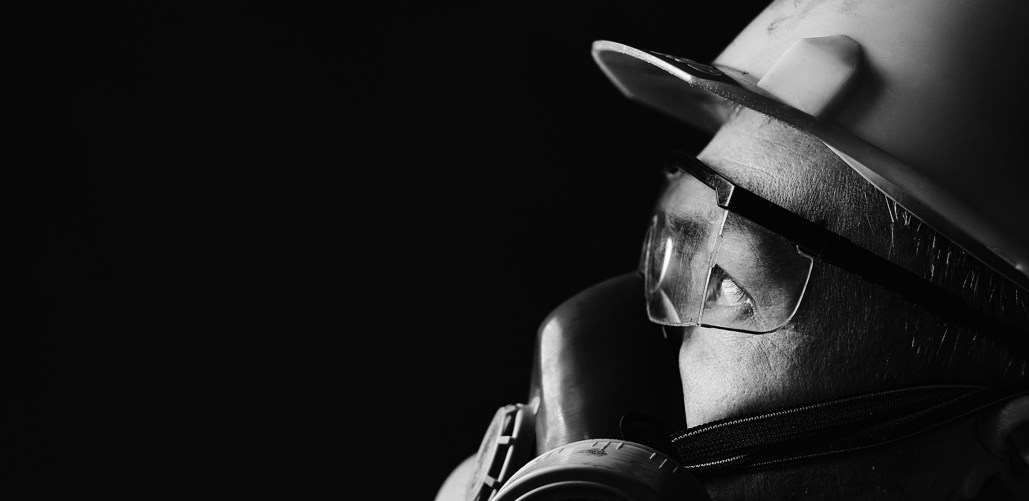 A man in a hard hat, safety goggles and a protective mask