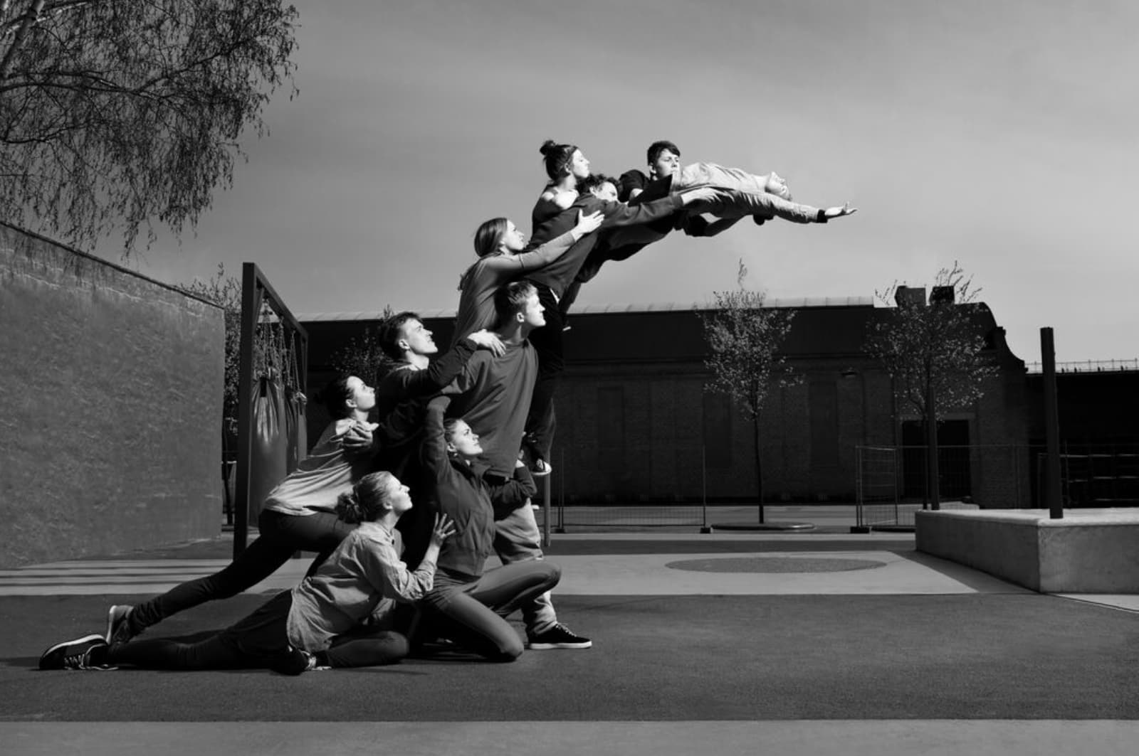 Young people creating a human statue, reaching out for the sky.