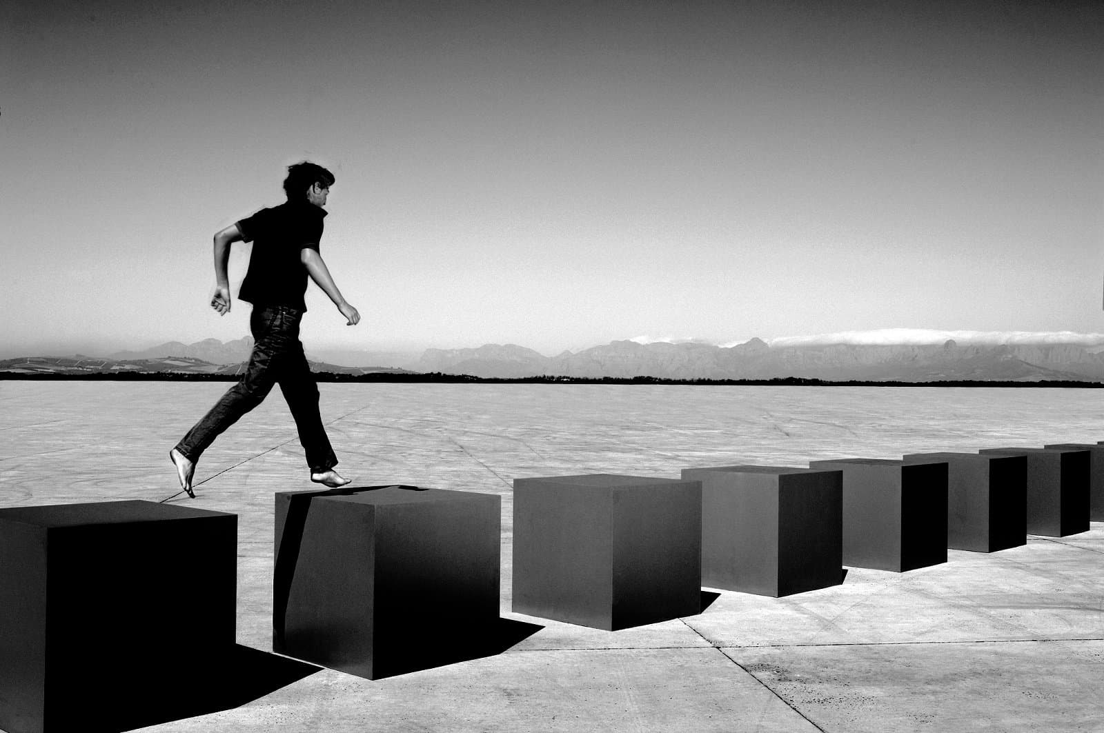 A person walking on row of large cubes in barren landscape