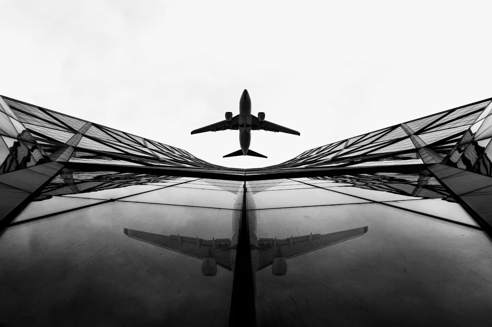 Airplane flying overhead with reflection on glass panels