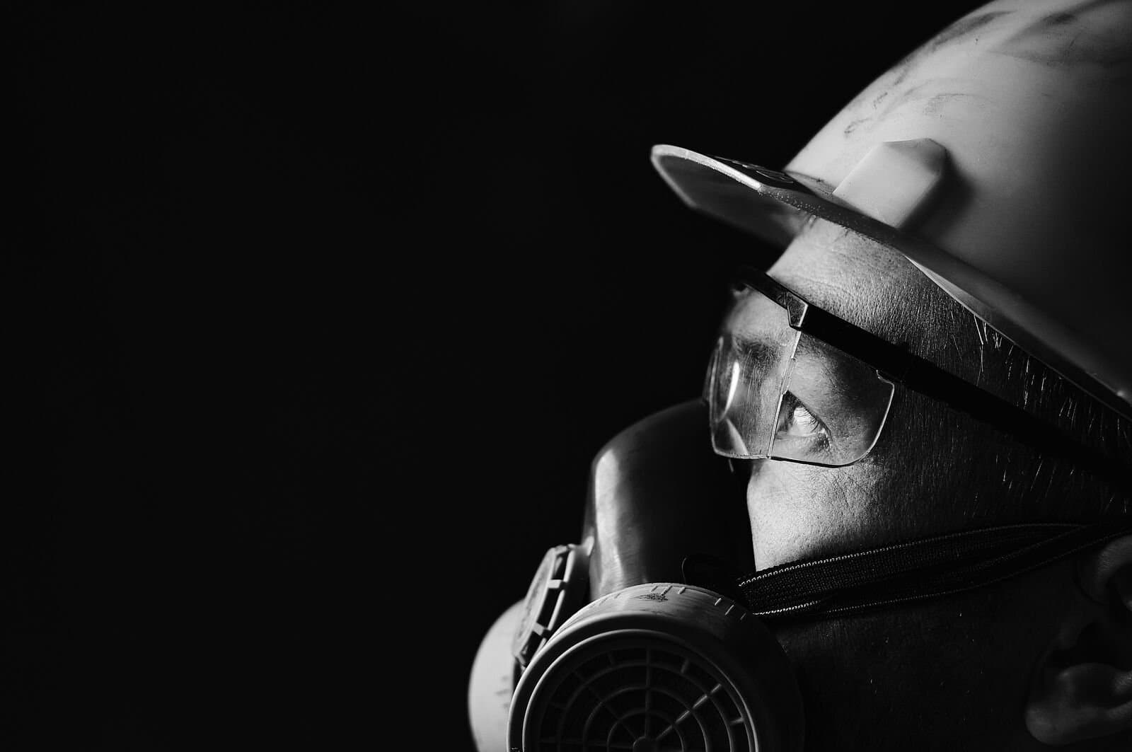 A man in a hard hat, safety goggles and a protective mask