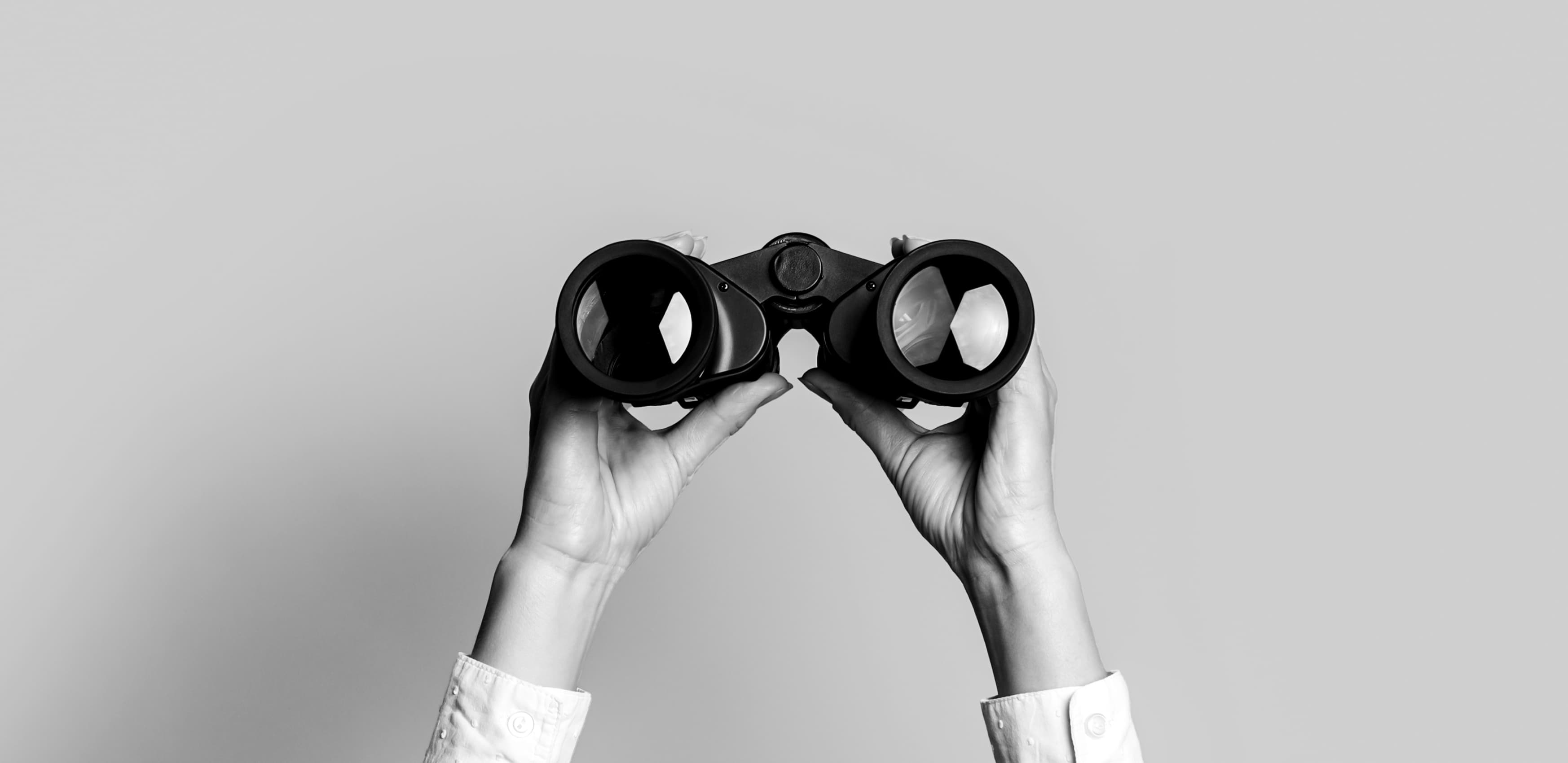 Female hands hold black binoculars