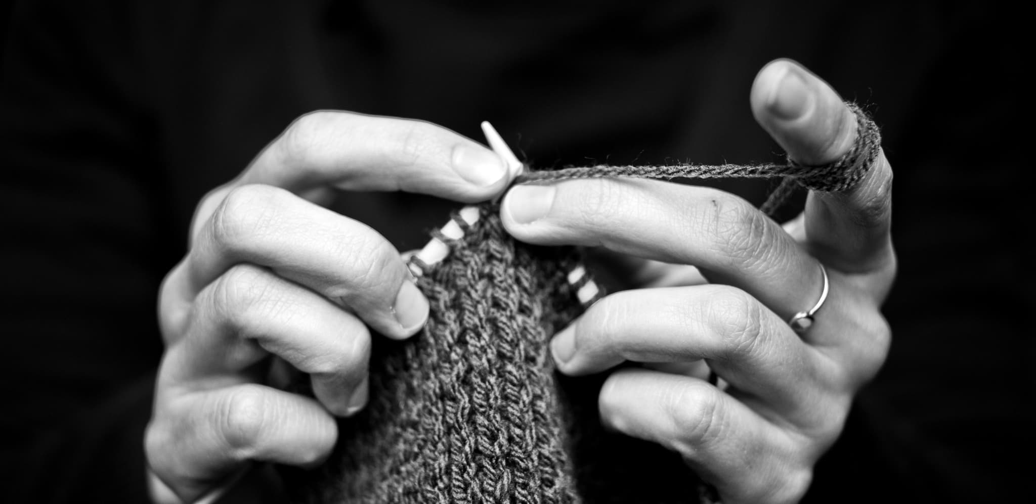 black and white close-up of two hands knitting